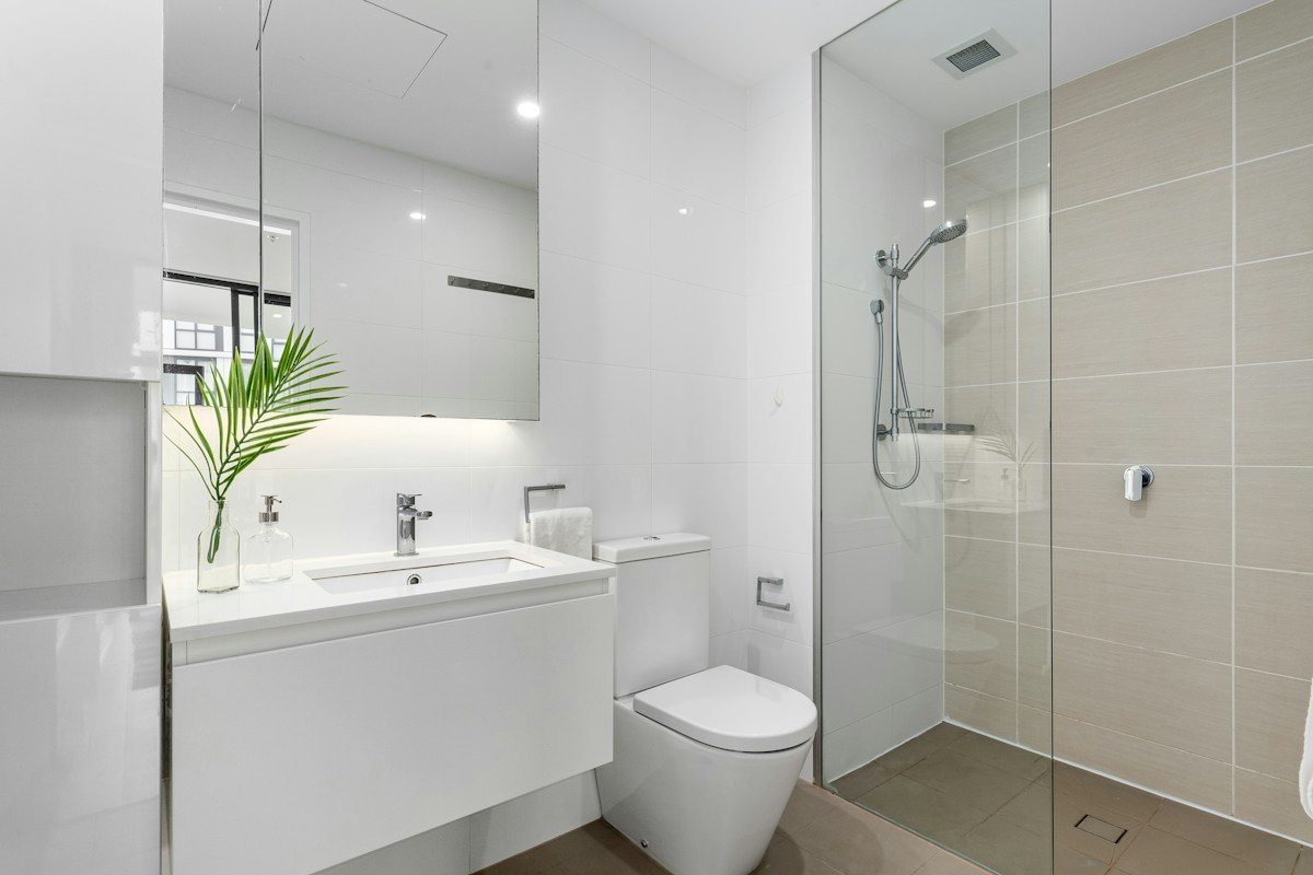 Freshly finished bathroom with clear shower glass, basin and tiled surfaces