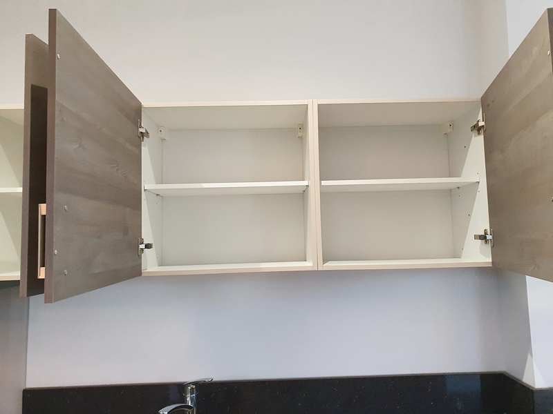 Open kitchen cupboard doors revealing clean, empty interior shelves