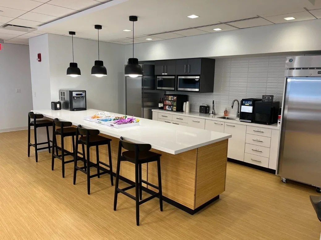Office kitchen and staff break room with shared counter, seating and appliances
