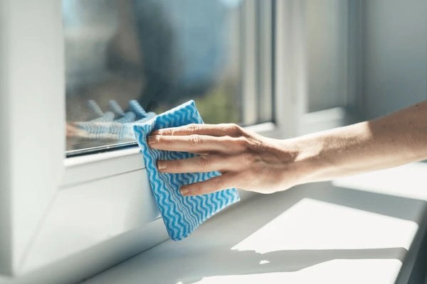 A microfibre cloth wiping dust from a window frame as a final cleaning detail